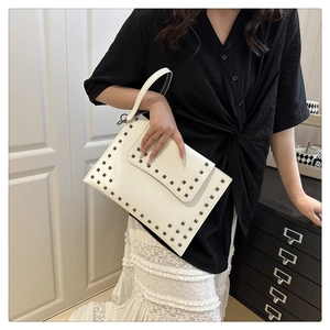 Close-up of white envelope clutch bag with silver square studs on matte leather texture