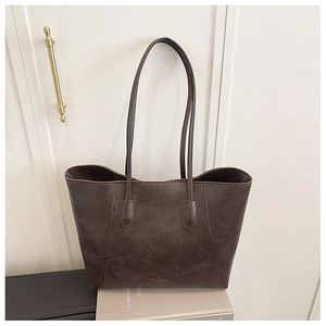 Detailed macro view of dark brown oil-wax leather texture and fine stitching on a tote bag