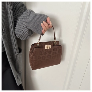 Detail of leopard print handbag with gold twist lock held by model in casual setting