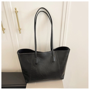 Detail of minimalist black tote bag with fine oil-wax texture and slim shoulder straps