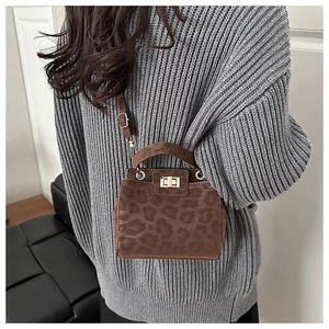 Detail of leopard print crossbody bag with golden turn-lock on a grey sweater