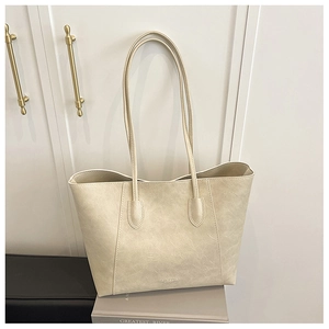 Macro view of beige tote bag showing vintage crinkled leather texture and gold logo