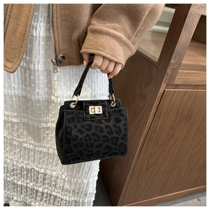 Close-up of leopard print handbag with gold twist lock and textured matte finish