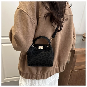 Détail d'un sac bandoulière léopard noir avec fermoir doré porté par un mannequin