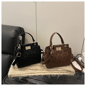 Detail view of leopard print bucket bags in black and brown with golden hardware clasp