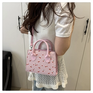 Modella che indossa una borsa rosa con stampa a ciliegie e tracolla staccabile