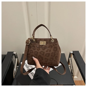Detail of leopard print bucket bag featuring gold twist lock and adjustable strap