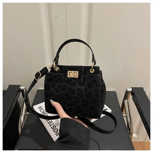 Detailed view of leopard print handbag with gold twist lock and adjustable strap