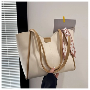 Detail of cream white tote bag with brown handles and a pink polka dot silk scarf