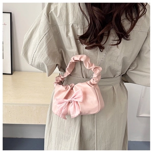Detail of pink pleated handbag with silk bow and silver chain strap on model