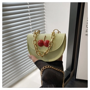 Dettaglio mini borsa a semicerchio verde chiaro con ciliegie 3D e catena dorata