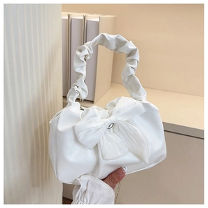Detail of a creamy white handbag featuring a large bow and pleated handle design