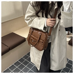 Brown vintage faux leather tote bag with bow detail shown on a model in a warm interior