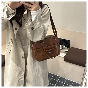 Detail of a brown tote bag with heart charm and bow accent in a mirror selfie