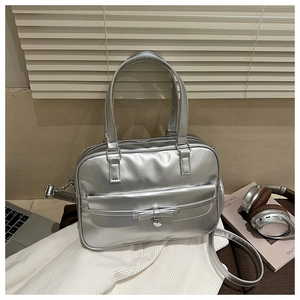 Detail of silver metallic bowling bag featuring a bow and heart pendant in a lifestyle setting
