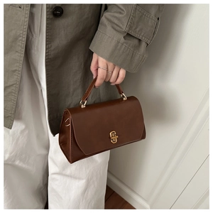 Detail of vintage dark brown faux leather square bag with gold geometric metal lock