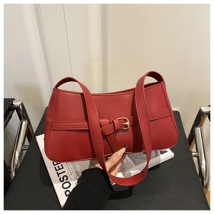 Close-up of red leather shoulder bag with vintage gold buckle and smooth texture