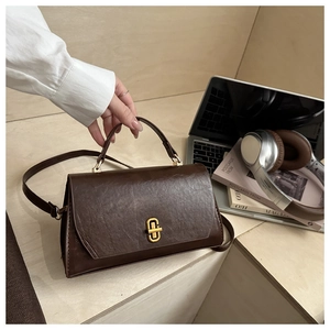 Detail of a vintage dark brown leather bag featuring a stylish gold ring clasp and top handle