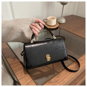 Detail shot of vintage black leather square bag with elegant gold rotating metal lock