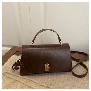 Detail of vintage brown textured leather handbag featuring a gold metallic twist lock
