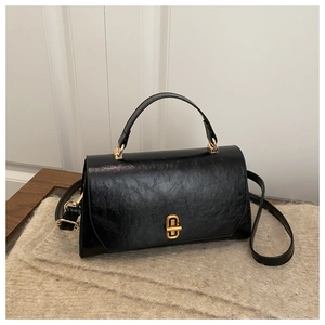Detail of vintage black mini square bag with glossy wrinkled texture and gold twist lock