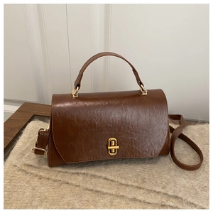 Detail of vintage dark brown faux leather bag with glossy finish and gold twist lock