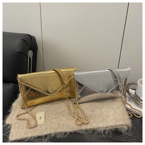 Detail of gold and silver envelope bags with ripple texture on a beige wool mat