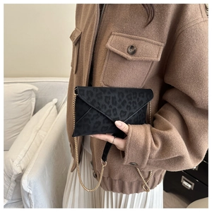 Elegante borsa a busta leopardata con catena dorata indossata da una modella chic
