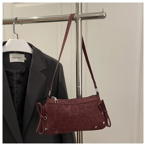 Detail of burgundy leopard texture shoulder bag with side bow accents and metal studs