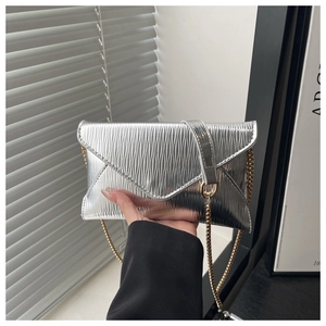 Close-up of metallic silver envelope bag with ripple texture and gold chain strap