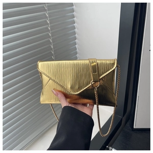 Detailed view of the gold metallic envelope bag with pleated texture and metal chain
