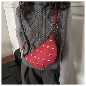 Close-up of red suede punk crossbody bag with gold studs on a model's chest