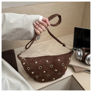 Detail of brown suede crescent bag with gold studs and metal eyelets in lifestyle scene
