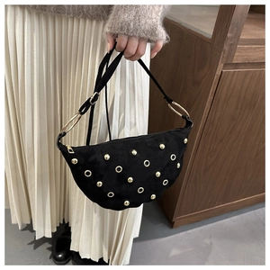 Detail of black crescent moon bag featuring gold rivets and matte suede texture