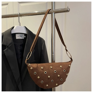 Close-up of brown suede hobo bag featuring gold rivets and industrial metal rings