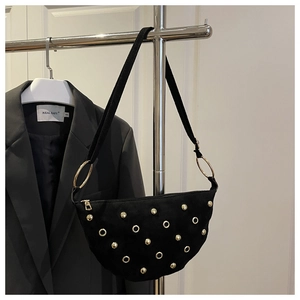 Detail of black crescent shoulder bag featuring gold studs and metal eyelets on canvas