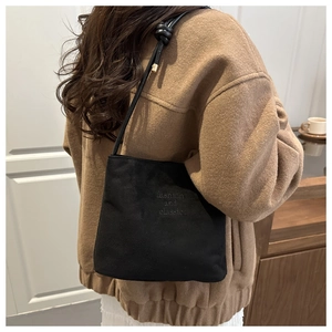 Gros plan du sac seau noir en daim avec l'inscription gravée fashion and classic
