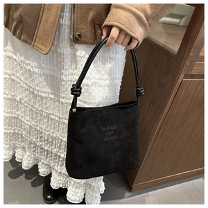Détail du sac seau noir mat avec poignée nouée et texte décoratif fashion et classic
