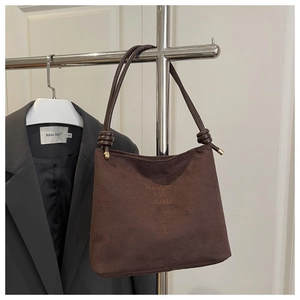 Gros plan du sac seau en daim marron avec broderie et bandoulière à nœud cylindrique