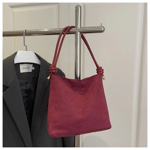 Détail du sac cabas en daim bordeaux avec poignées nouées et gaufrage de haute qualité