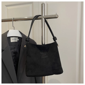 Détail du sac bandoulière en suédine noire avec anse nouée et embouts en métal doré