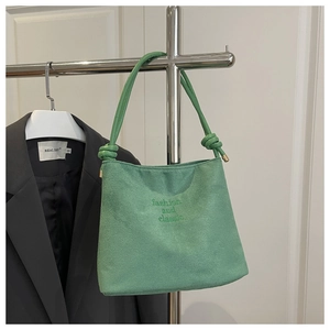 Détail du sac bandoulière en daim vert avec bandoulière nouée et broderie de mode