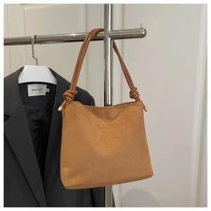 Détail du sac fourre-tout en daim marron avec anse nouée et texte fashion and classic