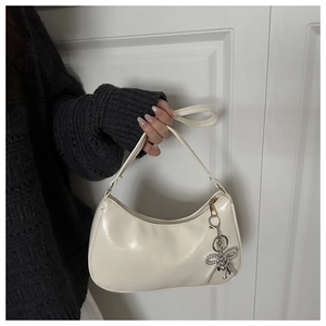Detailopname van witte PU-lederen hobo-tas met een decoratieve zilveren strikhanger