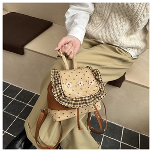Close-up of floral stitching and polka dot fabric detail on this mini backpack
