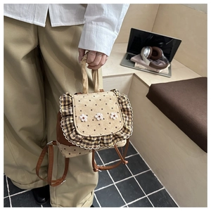 Mini backpack detail featuring beige polka dots with floral embroidery and ruffle trim