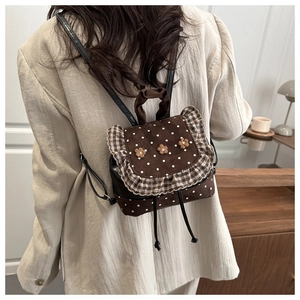 Close-up of brown polka dot mini backpack featuring 3D floral accents and ruffle trim detail