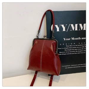 Detail of dark red vintage kiss-lock bag with white contrast stitching and gunmetal clasp