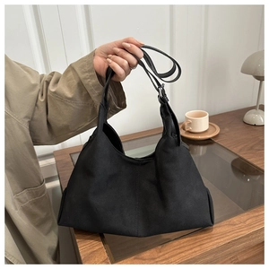 Detail of a vintage black suede tote bag with adjustable strap in a cozy cafe setting