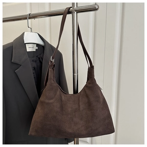 Detail view of dark brown suede tote bag with adjustable strap on minimalist hanger